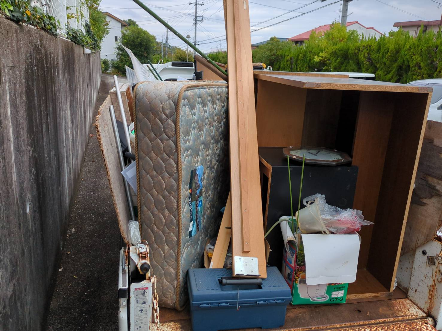 和泉市光明台で回収した不用品を軽トラック荷台へ積み込んだ後の状態を真後ろから撮影。ベッドやマットレスなどの大型不用品が積載済み