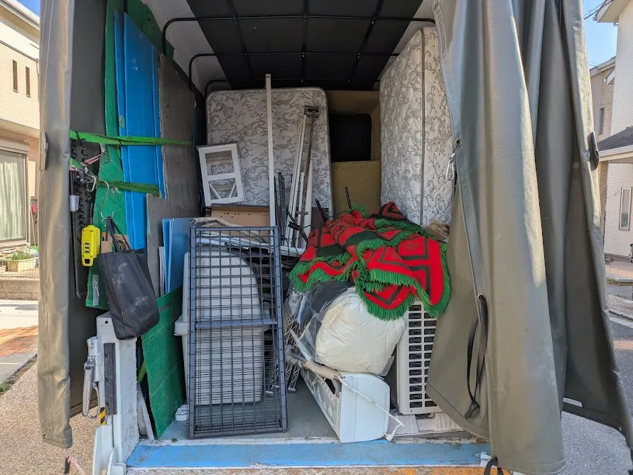 2トン幌付きトラックの荷台にエアコン・マットレス・ベッドなど不用品を積み込み